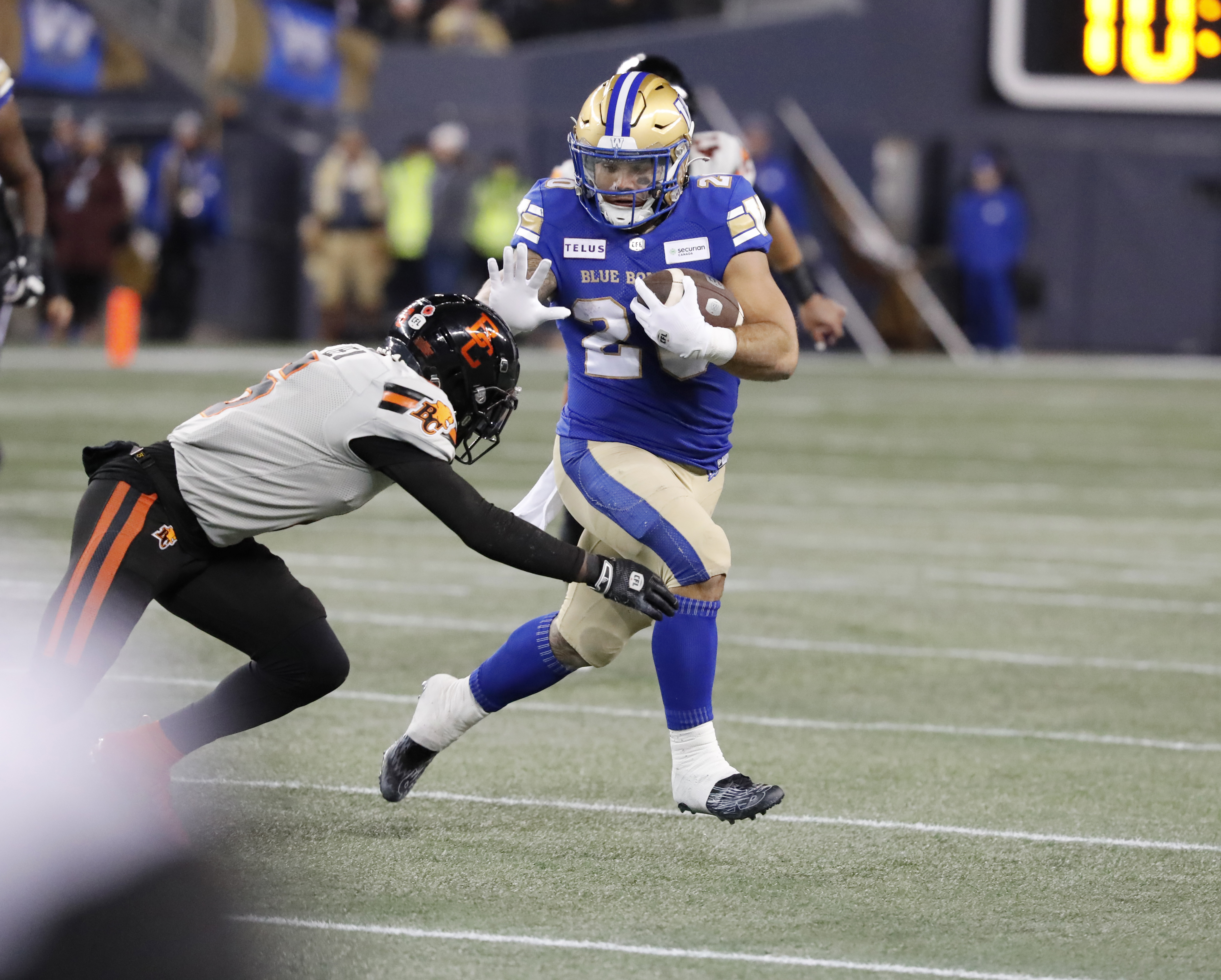 Nov 11, 2023; Winnipeg, Manitoba, CAN; Winnipeg Blue Bombers running back Brady Oliveira (20) breaks a tackle by BC Lions defensive back T.J. Lee (6) during the first half of the game at IG Field. Mandatory Credit: Bruce Fedyck-USA TODAY Sports